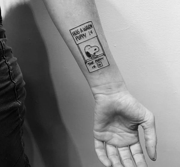 Black and white tattoo on a person's forearm featuring Snoopy inside a vending machine design with the text "Hug a warm puppy 1¢.