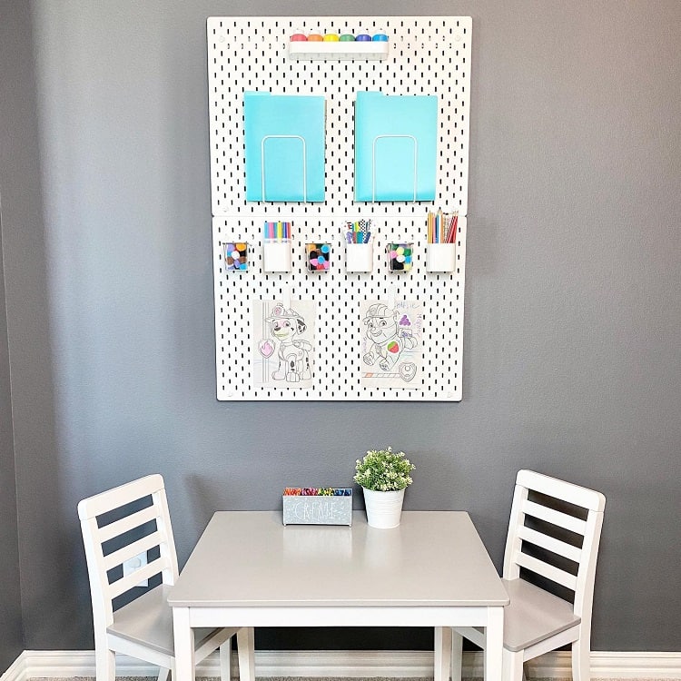 Kids' play area with a craft board, table, chairs, art supplies, and decorative items on a gray wall