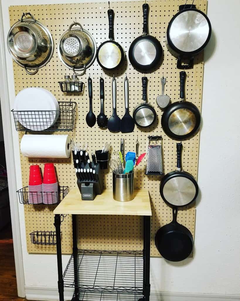 kitchen pegboard with pots and pans and wall shelf