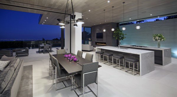 Modern open living and dining area with a large table, kitchen island, and island view at dusk