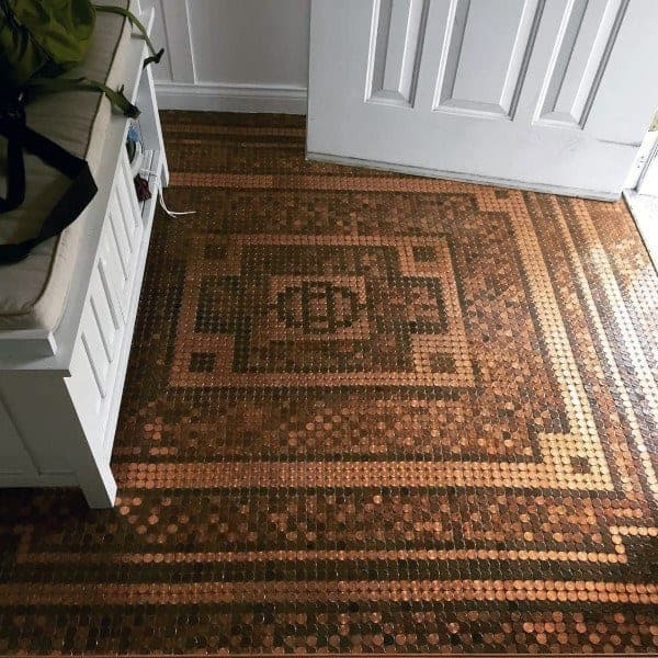 Intricate penny floor design in an entryway with a geometric pattern near a white door.