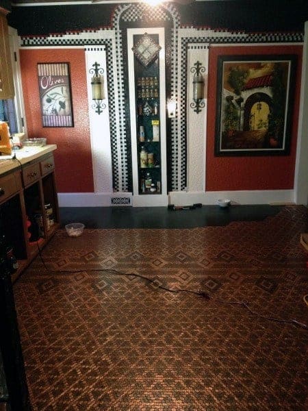 Kitchen with intricate penny tile flooring, decorative wall art, and warm red accent walls.