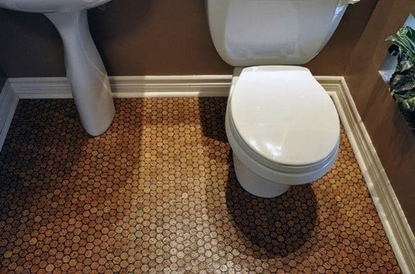 Bathroom with penny tile flooring, pedestal sink, and white toilet against beige walls.