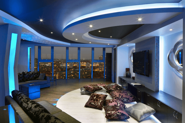 Modern living room with curved ceiling, blue LED lights, and plush cushions perfect for a cozy home theater ambiance