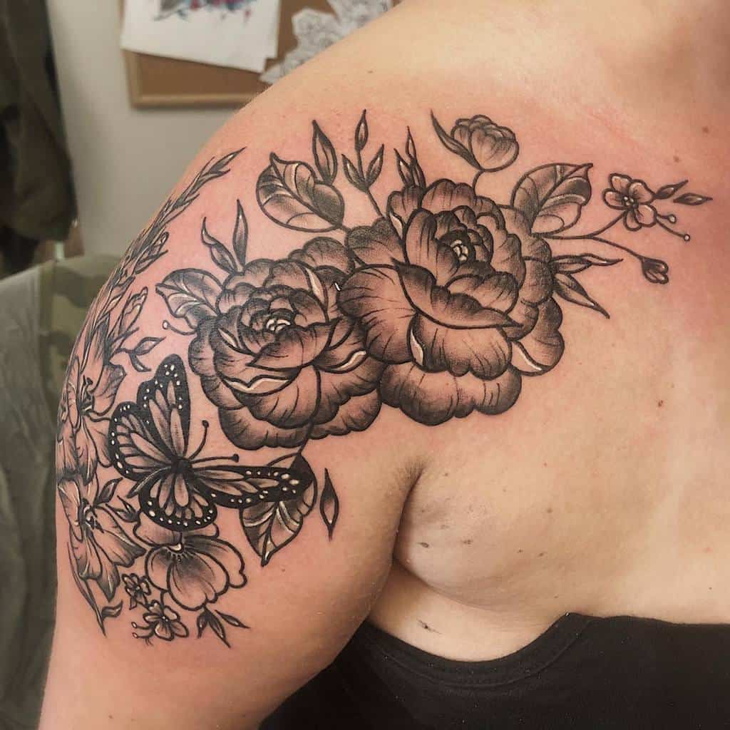 Black and grey peony shoulder tattoo with a butterfly and delicate floral details, covering the upper arm