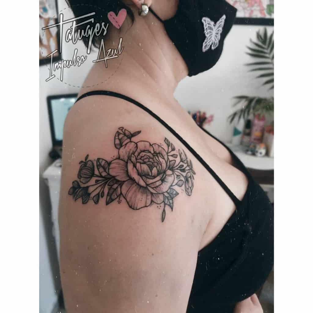 Black and grey peony shoulder tattoo with buds and leaves, delicately designed on the upper arm