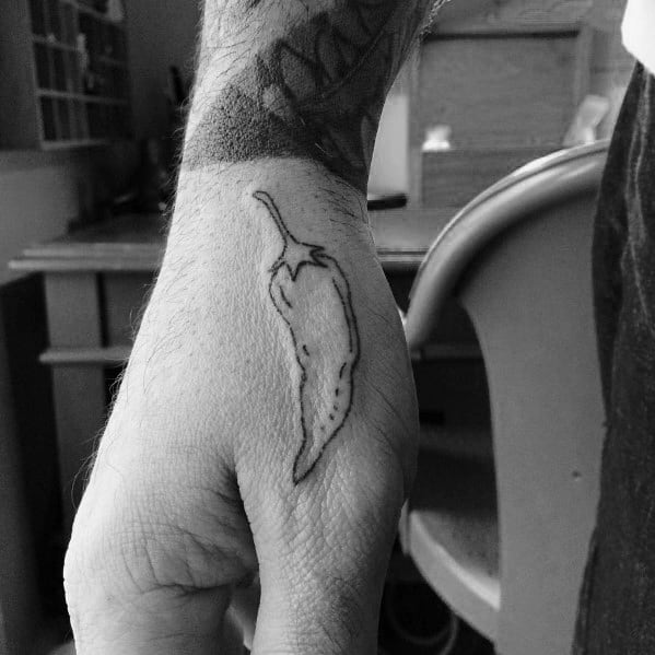 Minimalist black ink chili pepper tattoo on the hand with fine line details, creating a simple yet bold design.