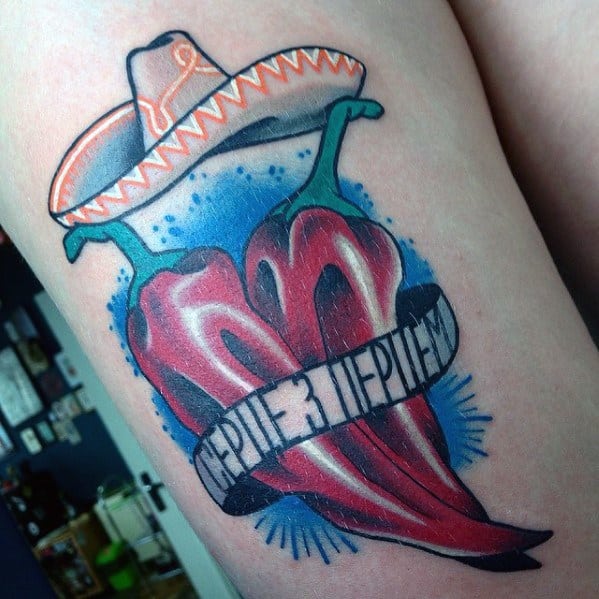 Tattoo of two red chili peppers forming a heart, topped with a sombrero and a banner with Cyrillic text, featuring bold colors and shading.