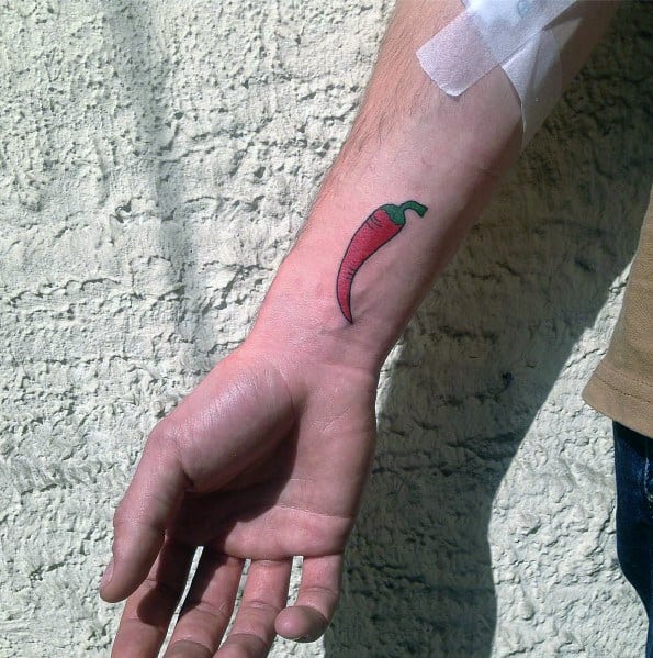 Simple red chili pepper tattoo on the forearm with a green stem, featuring clean lines and subtle shading for a minimalist yet bold design.