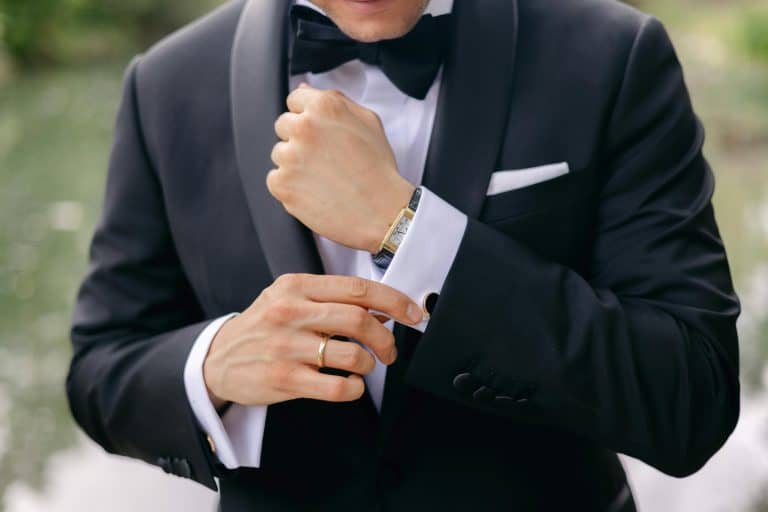 Formal Attire for Men - What You Need to Know closeup of a mana adjusting is cuff wearing a classic black and white tuxedo