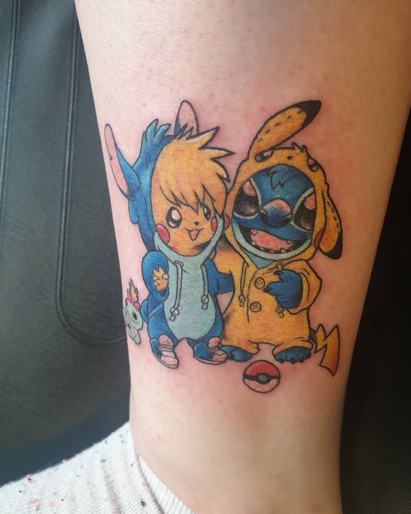 Colorful tattoo of Stitch and a character wearing a Pikachu hoodie, both with playful expressions and surrounded by Pokémon elements, on the lower leg.