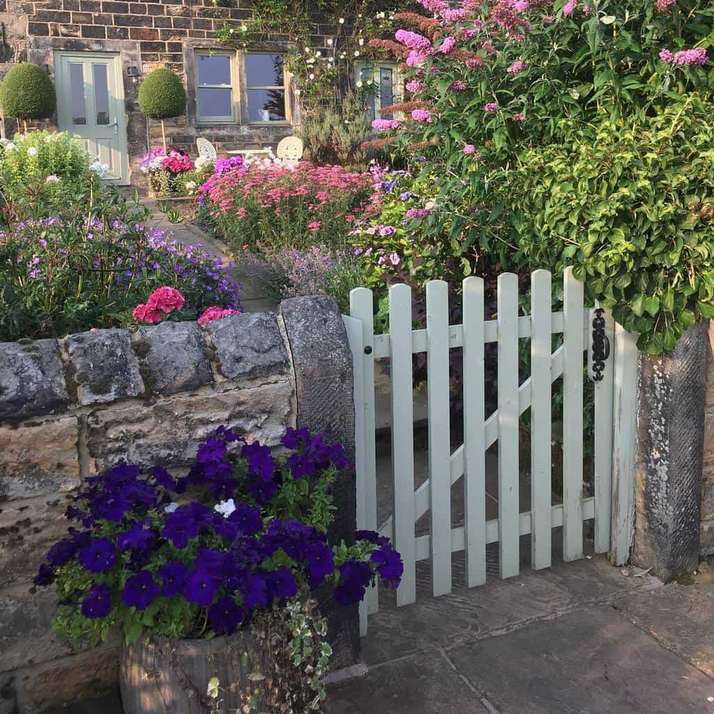 white picket garden gate stone wall flowers