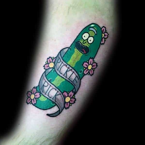 Pickle Rick tattoo wrapped in a ribbon with 'Pickle Rick' text, decorated with pink flowers, featuring a fun and playful design on the arm.