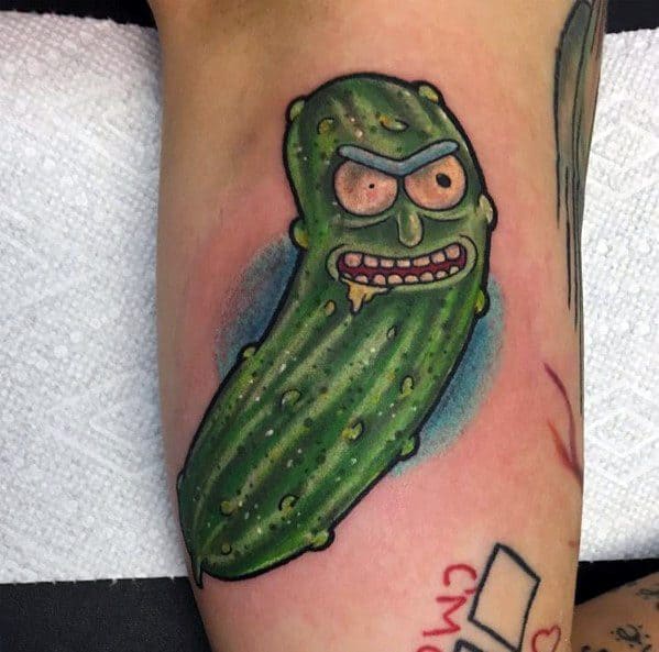 Pickle Rick tattoo with a fierce expression, bold outlines, and realistic pickle texture, featuring vibrant green shading on the arm.