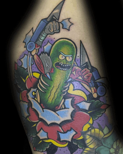 Bold Pickle Rick cyborg tattoo with vibrant colors, dynamic action pose, and sharp weapons, surrounded by a colorful floral design.
