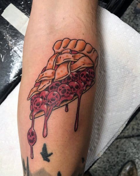 Dark-themed cherry pie tattoo with a lattice crust and dripping filling made of skulls, blending horror and surrealism for a bold, edgy design