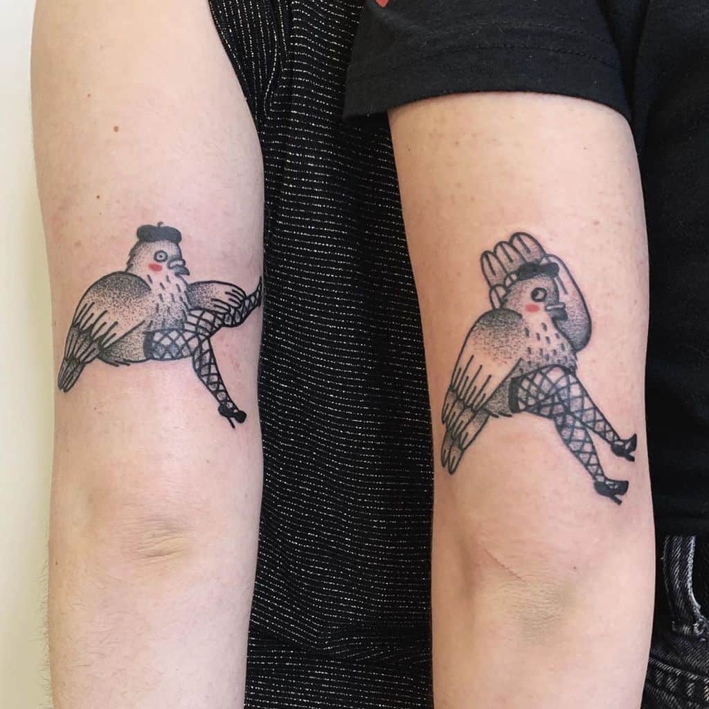Matching tattoos of chickens with human legs wearing fishnet stockings and heels, drawn in a humorous and bold style on the arms.