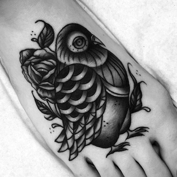 Blackwork pigeon tattoo on foot with bold lines, rose detailing, and soft shading, merging elegance with traditional style.