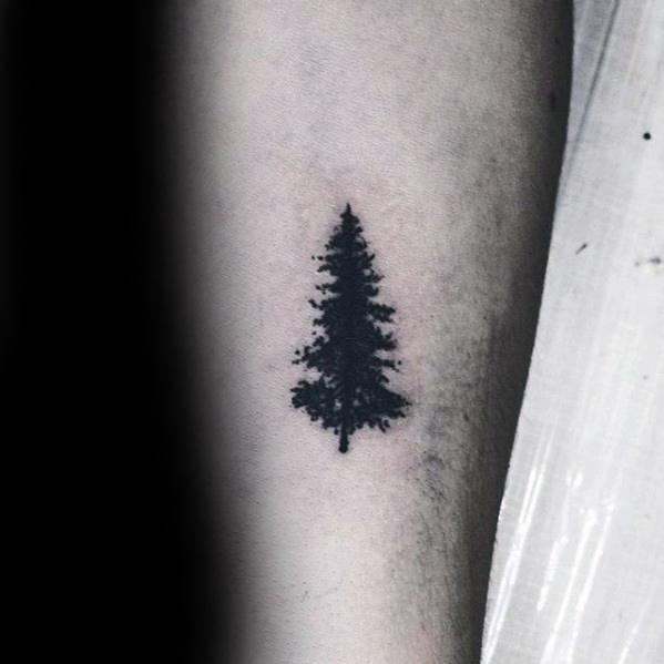 Black silhouette of a pine tree tattoo on an arm