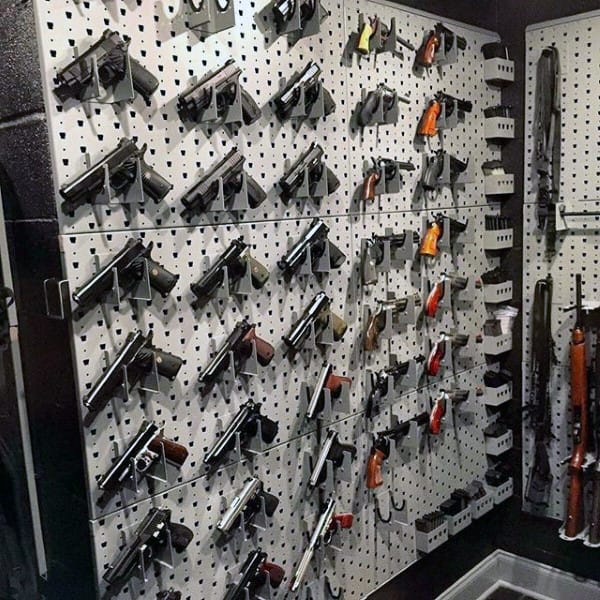Gun room with pegboard walls displaying an organized collection of pistols and accessories.