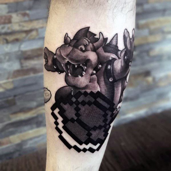 Black and grey Bowser tattoo on a man's leg featuring bold shading, dynamic details, and a pixelated effect for a unique Mario-inspired design.
