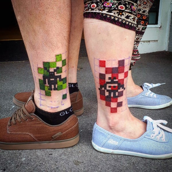 Matching pixel art tattoos of a green and red 8-bit character on ankles, symbolizing a playful, nostalgic love rooted in gaming.