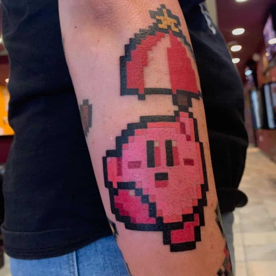 Pixel art-style Kirby tattoo holding a red parasol with a star on top