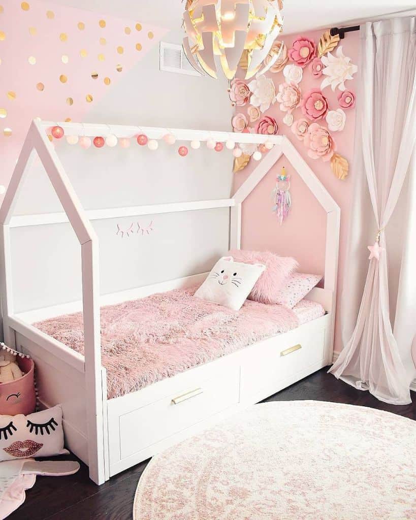 Pink-themed kids' bedroom with white bed frame, wall flowers, and cozy decor.