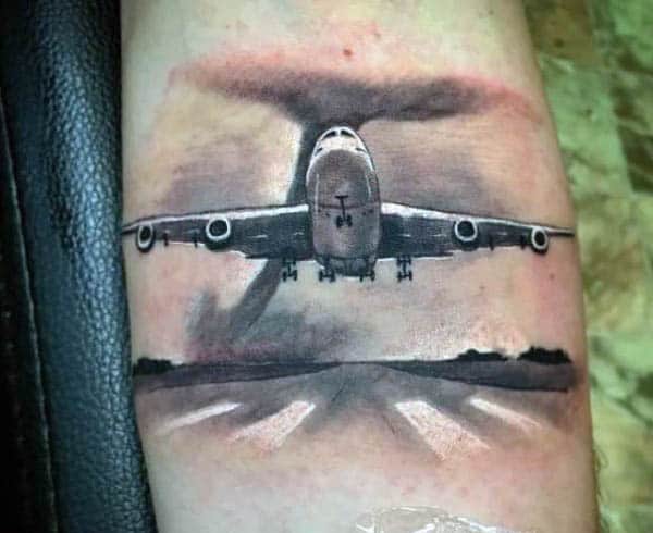 Tattoo of an airplane soaring into the sky with a detailed runway and vibrant cloudscape in the background