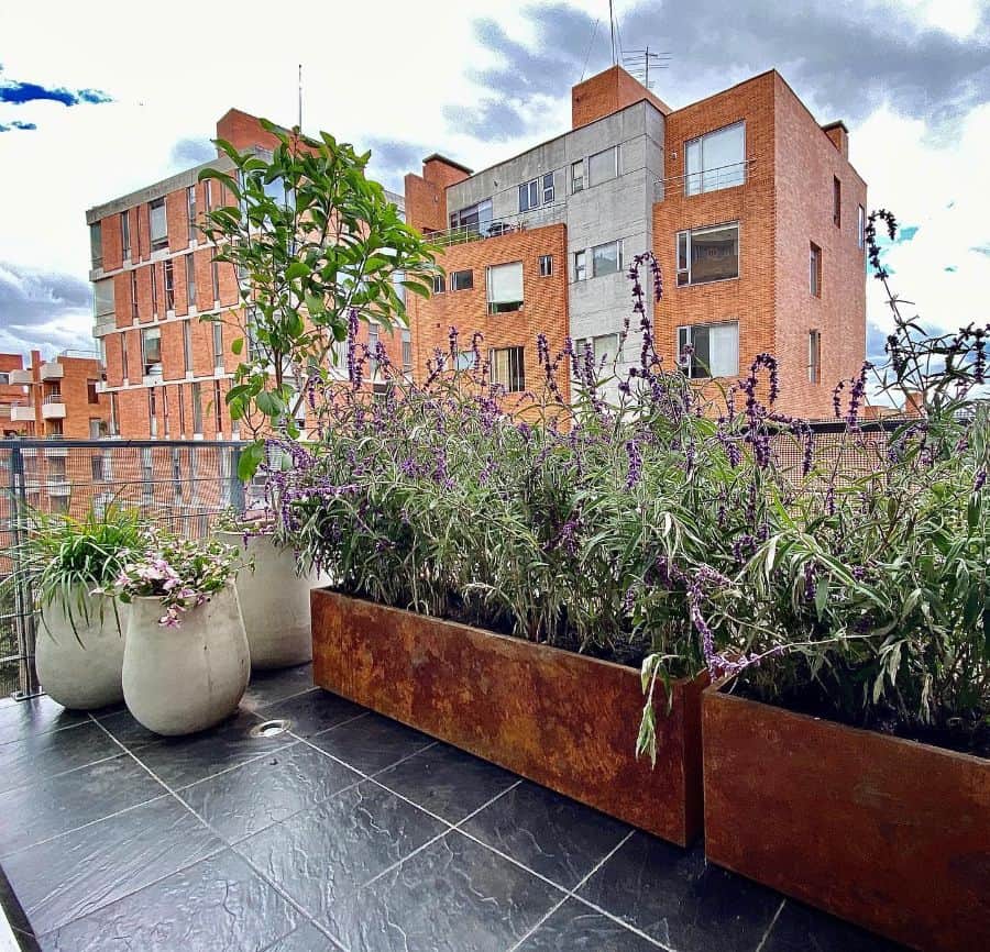 Modern balcony with lavender planters and potted greenery on a tiled floor.