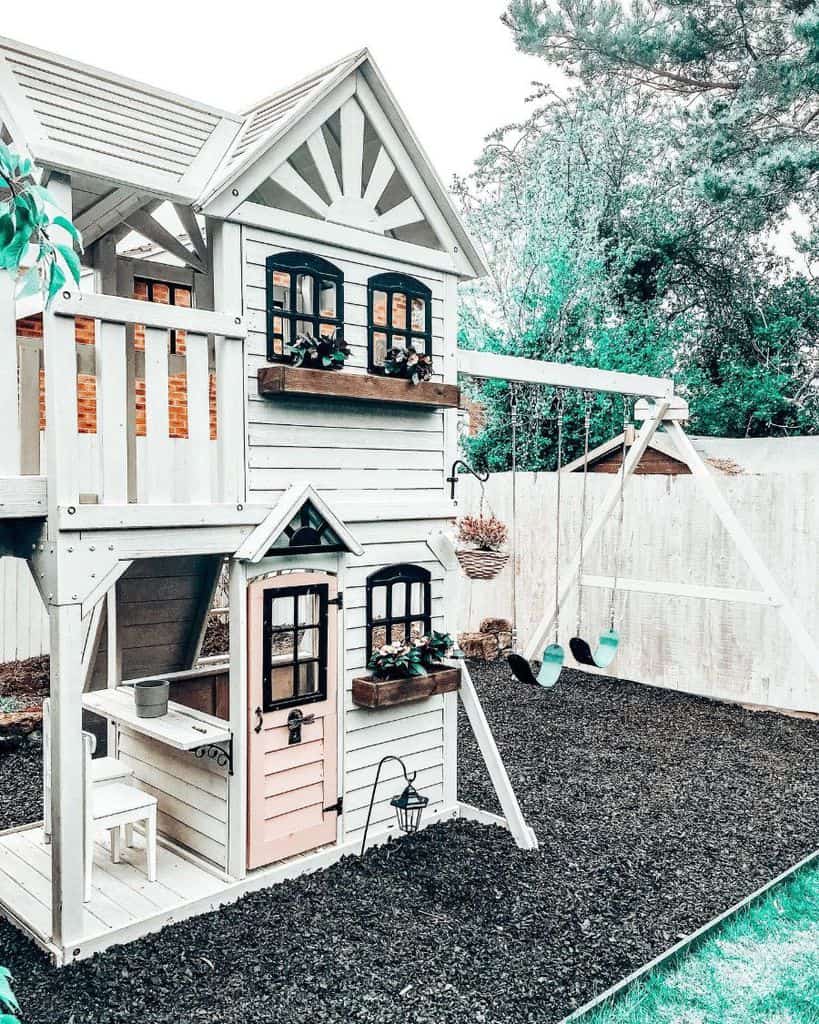 large white backyard playhouse with swings