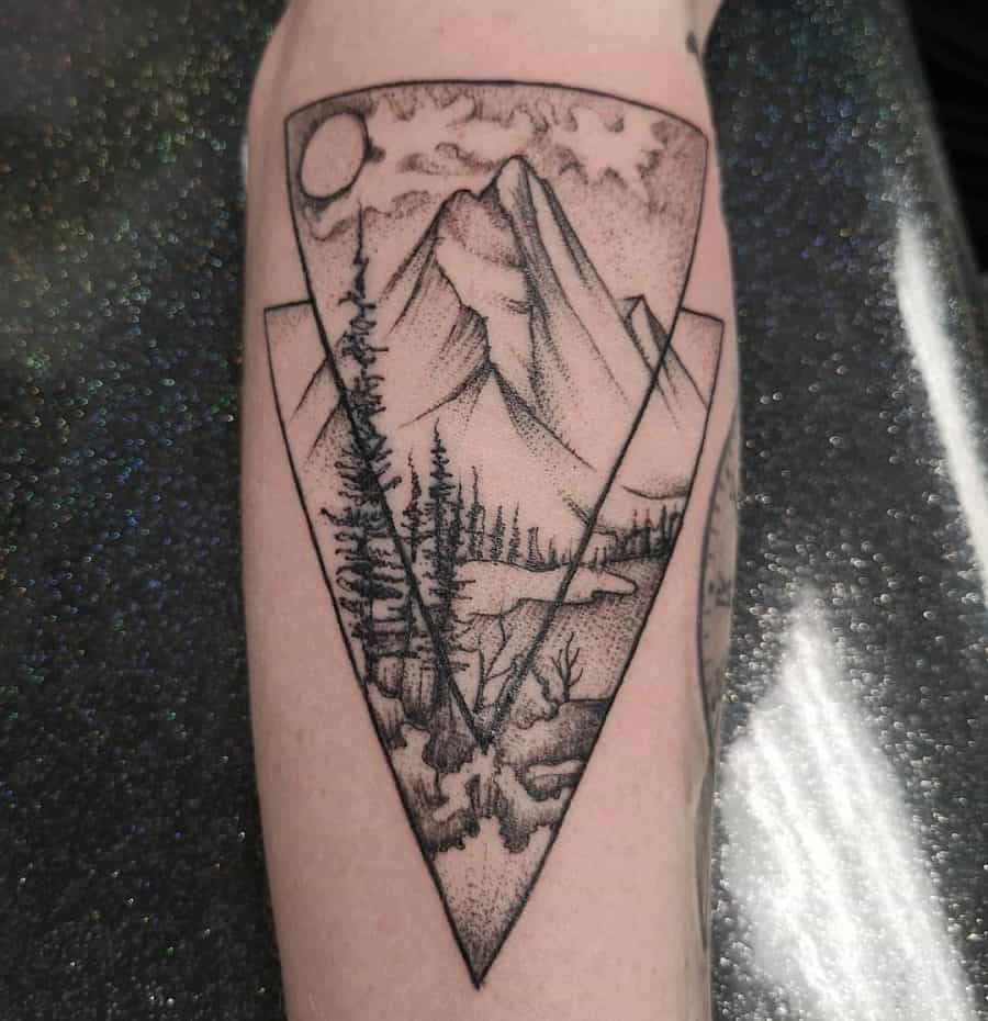 Forearm tattoo of a mountain landscape framed within geometric shapes, using fine line and dot work for a detailed nature-inspired design.