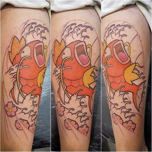 Large Magikarp thigh tattoo in progress with bold outlines, cherry blossoms, crashing waves, and bright orange and yellow coloring.