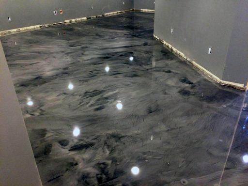 Shiny, marbled gray concrete floor in a dimly lit room with unfinished walls