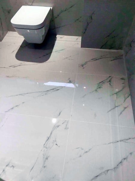 Polished white marble floor tiles with subtle gray veining in a modern bathroom.