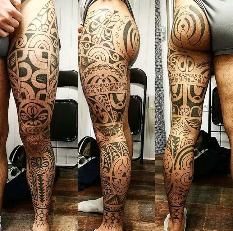 Detailed tribal leg sleeve tattoo with bold geometric shapes, featuring intricate patterns and designs 