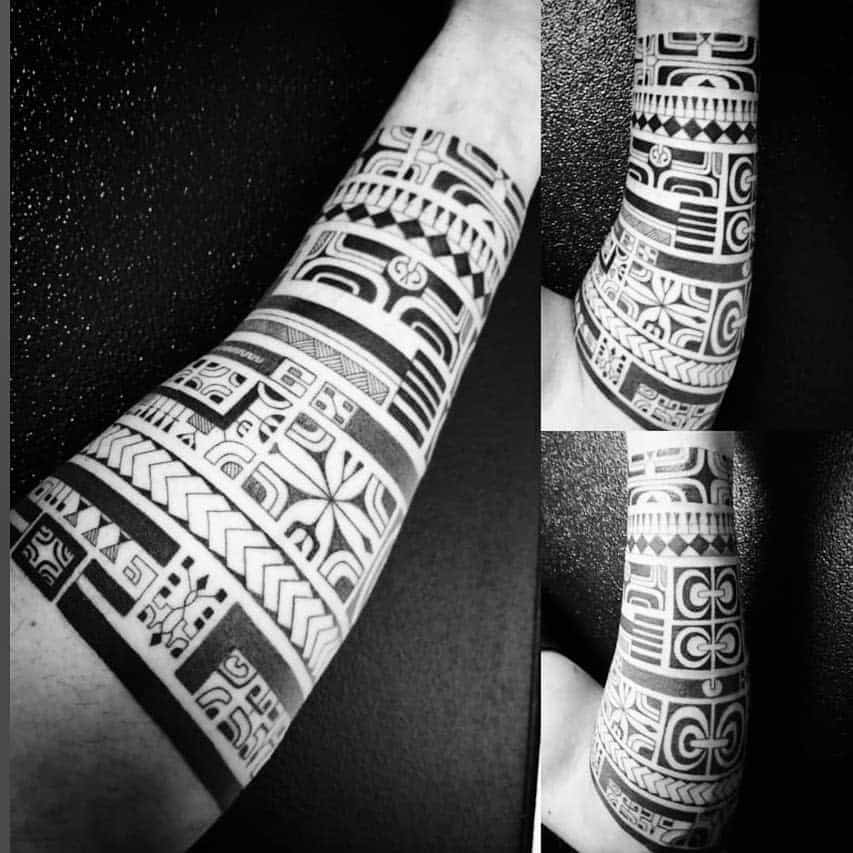 Polynesian-inspired forearm tattoo with bold black bands and intricate geometric patterns, creating a striking visual effect