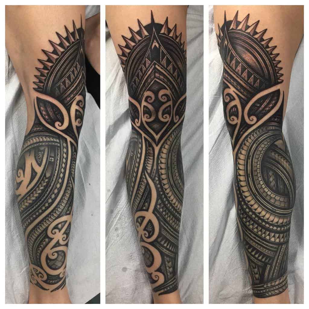 Bold tribal arm sleeve tattoo featuring geometric patterns, sharp lines, and intricate designs with swirling motifs and shaded details