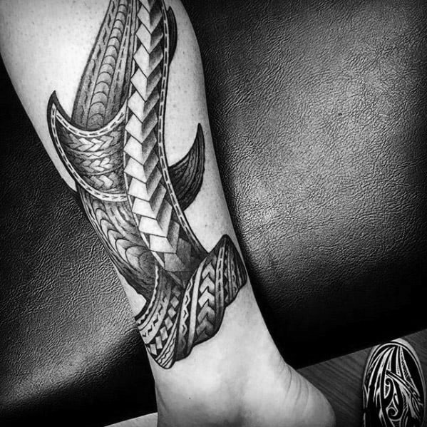 Polynesian shark tattoo on lower leg with bold geometric patterns and flowing tribal details symbolizing strength, direction, and resilience.