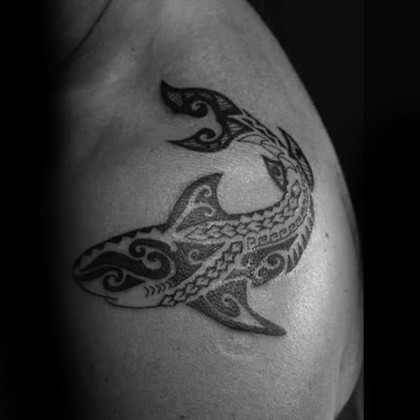Polynesian shark tattoo on shoulder with bold tribal patterns symbolizing protection, strength, and connection to ancestral ocean roots.