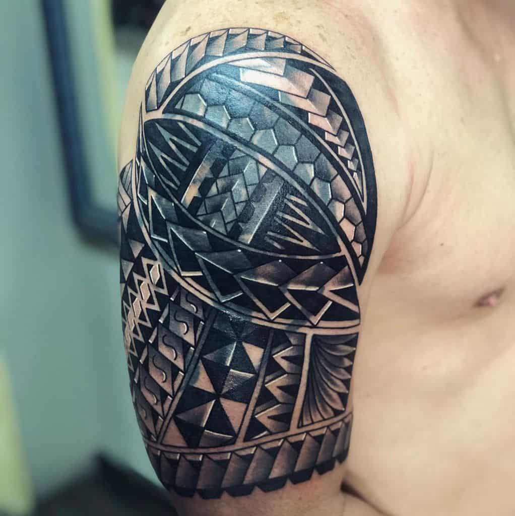 Tattooed shoulder with intricate geometric and tribal Polynesian patterns in black ink