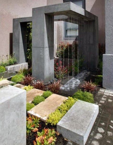 Modern rainwater feature with concrete arches, lush greenery, and minimalist landscaping.