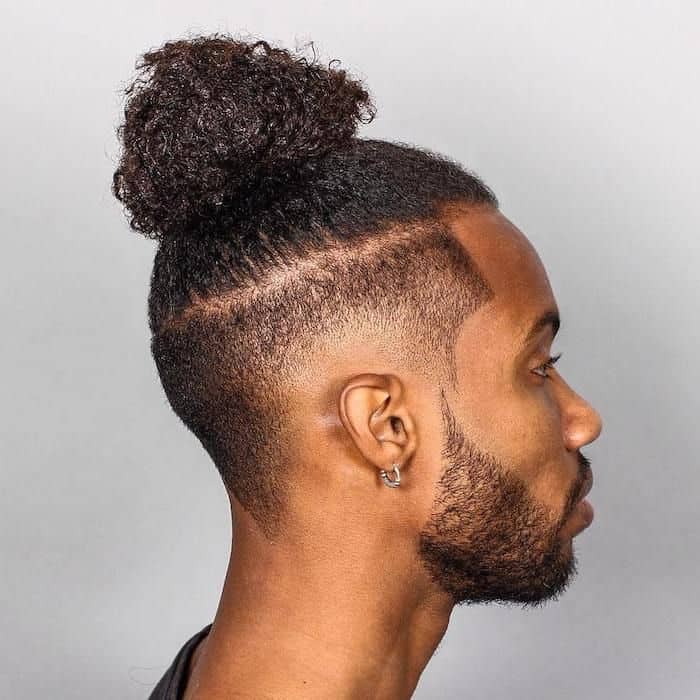 Long hair styled into a ponytail man bun paired with a burst fade