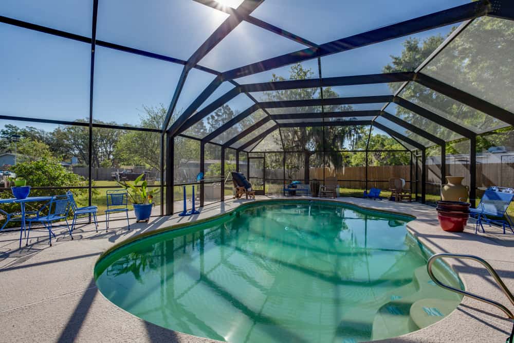 large enclosed pool patio glass walls and ceiling blue outdoor furniture 