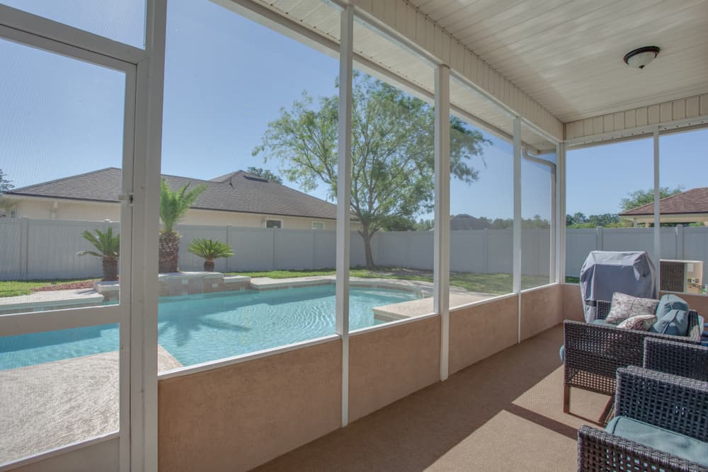 large backyard pool enclosed patio wicker furniture 