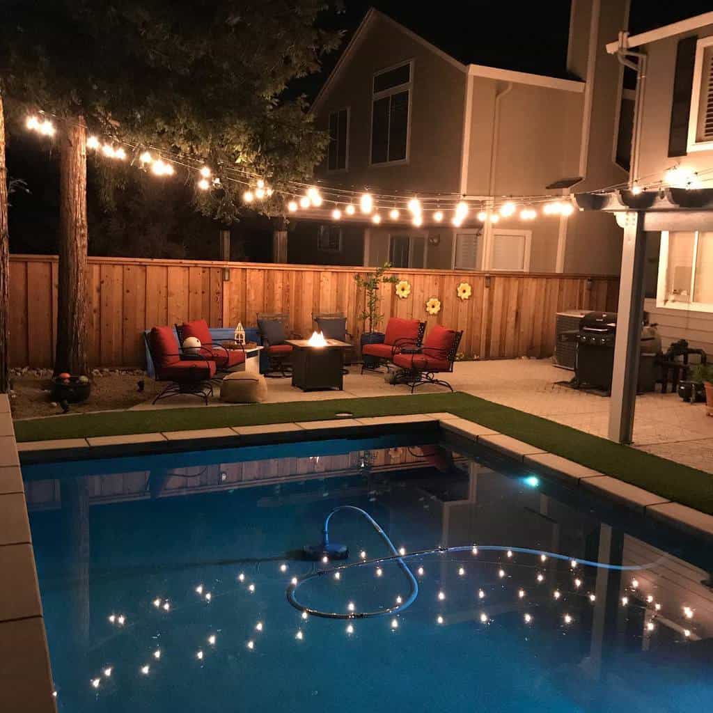 string lights over backyard pool and patio with fire pit