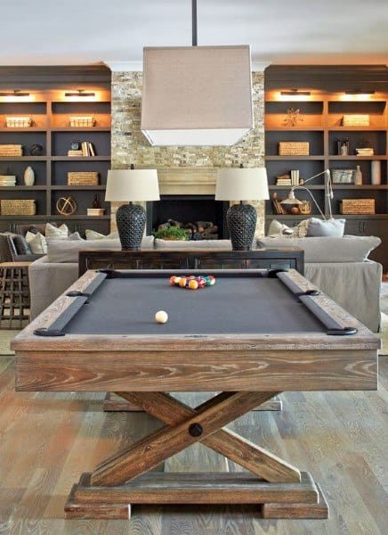 Basement with modern pool table, built-in bookshelves, fireplace, and large square pendant light.