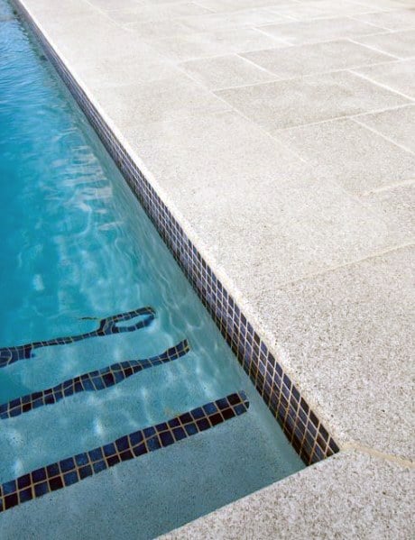 Elegant pool design showcasing dark mosaic tiles on steps and waterline, contrasting beautifully with a light-toned deck.