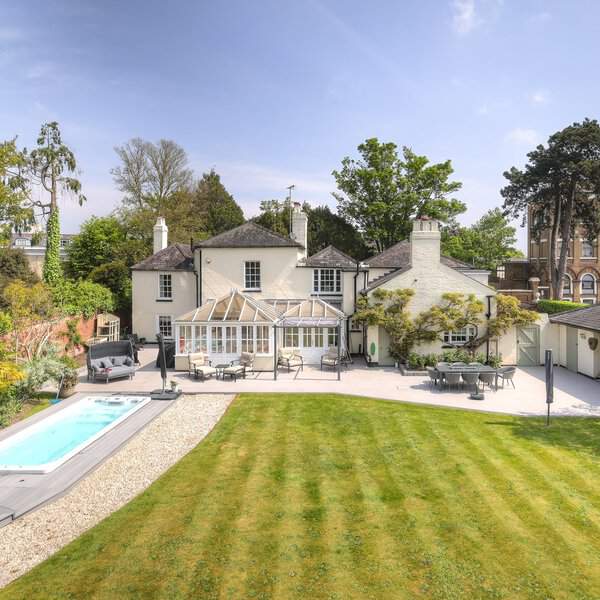 A beautiful Georgian-style home with a sleek pool and surrounding outdoor seating area for leisure and entertainment.