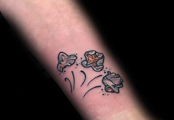 Tattoo of three popping popcorn kernels with motion lines and shading, captured in a fun and dynamic minimalist style.